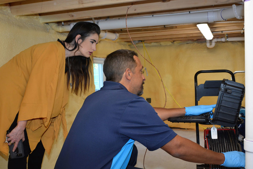 Z PLUMBERZ plumbing franchise opportunity plumber inspecting sewer and drain with customer